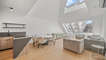 Helles Dachgeschoss-Apartment mit offener Küche, Essbereich und Wohnzimmer unter schrägen Decken und Dachfenstern.