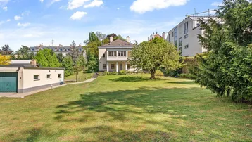 Großzügiger Gartenbereich mit viel Grünfläche und einem freistehenden Haus im Hintergrund.