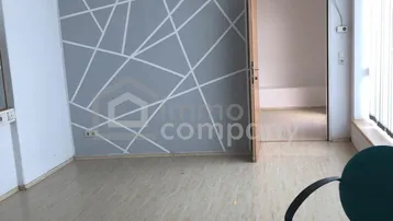 Leerer Büroraum mit modern gestalteter Wand, Laminatboden und abgehängter Decke.