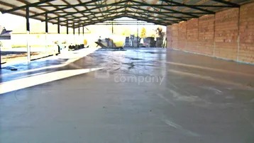 Große, leere Halle mit Betonboden und offener Stahlkonstruktion.