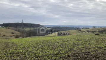 Weite Landschaft mit Feldern und Hügeln unter einem bewölkten Himmel, ideal für Naturliebhaber.
