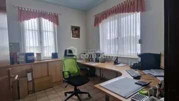 Helles Büro mit zwei Fenstern, Schreibtisch und ergonomischem Stuhl, ideal für konzentriertes Arbeiten.