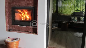 Eingebauter Kamin mit Ziegelverkleidung und brennendem Feuer, der zum Wohnbereich führt.