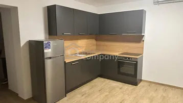 Moderne Küche mit dunkelgrauen Schränken, Holzrückwand und integrierten Geräten.