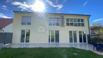 Helle Rückseite des Hauses mit großer Terrasse, Rasenfläche und Blick in den Garten.