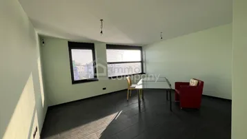 Helles Zimmer mit dunklen Fliesen, großen Fenstern und minimalistischer Einrichtung.