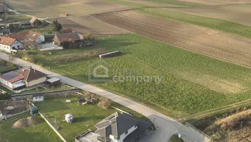 Luftaufnahme eines modernen Hauses in ländlicher Umgebung mit angrenzenden Feldern und einer Brücke.