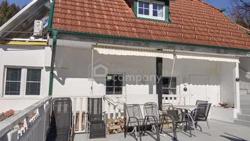 Geräumige Außenterrasse mit Sitzgelegenheiten, Markise und Blick auf das Haus mit Ziegeldach.