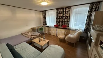 Gemütliches Wohnzimmer mit Holzboden, Sofa, Beistelltisch und Blick nach draußen durch die Fenster.