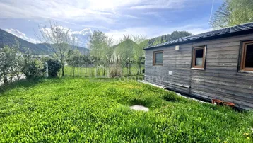 Grüner Gartenbereich neben dem Holzhaus mit Blick auf die umliegende Berglandschaft.