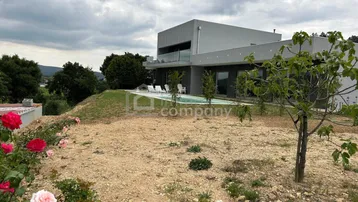 Moderne Villa mit Infinity-Pool und weitem Blick über die Landschaft unter bewölktem Himmel.