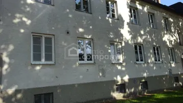 Fassade eines Mehrfamilienhauses mit mehreren Fenstern, die natürliches Licht hereinlassen, und sichtbaren Dachfenstern.