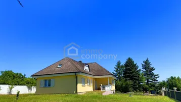 Gelbes Einfamilienhaus mit Satteldach und großem Garten auf einem sonnigen Grundstück.