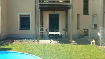 Gartenbereich mit kleiner Terrasse, Balkon und Aufstellpool vor der Gebäudefassade.