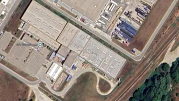Luftaufnahme eines großen Industriekomplexes mit mehreren Hallen und Parkplätzen.