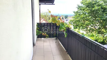Balkon mit Fliesenboden, Holzzaun und weitem Blick über die Landschaft.