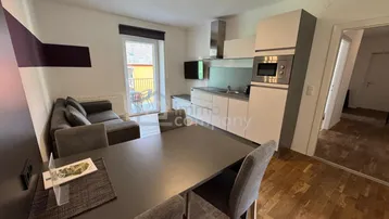 Heller Wohn- und Essbereich mit integrierter Küchenzeile und Zugang zum Balkon.