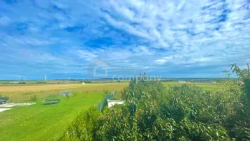 Weitläufiger Blick über grüne Felder und Landschaft unter einem bewölkten Himmel.