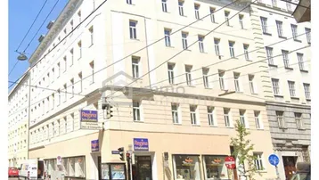 Gebäudeansicht von der Straße mit Geschäften im Erdgeschoss und Wohnungen darüber in einer städtischen Umgebung.