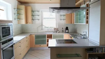 Helle Einbauküche mit Holzfronten, Kochinsel und modernen Geräten.