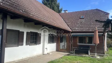 Seitenansicht des Hauses mit Eingangsbereich, Ziegeldach und angrenzender Grünfläche.