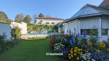 Gepflegter Garten mit kleinem Pool, üppigen Blumenbeeten und viel Grünfläche unter blauem Himmel.