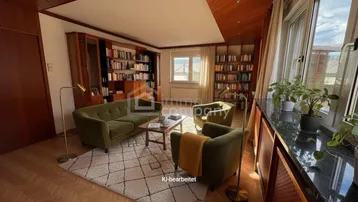 Gemütliches Wohnzimmer mit Holzdecke, Parkettboden, Bücherregalen und Blick ins Grüne.