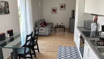 Helles Wohn- und Esszimmer mit integrierter Küchenzeile und Zugang zum Balkon.