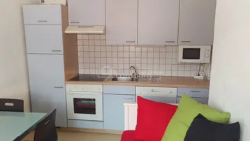 Kleine, funktionale Küche mit hellblauen Schränken, Holzarbeitsplatte und integrierten Geräten.