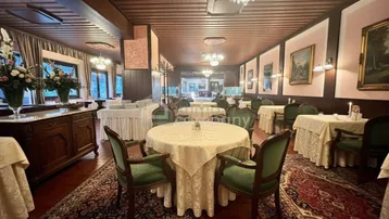 Traditioneller Speisesaal mit elegant gedeckten Tischen, Teppichboden und Kronleuchtern, ideal für Veranstaltungen.