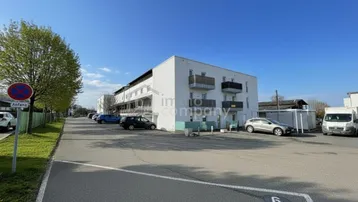 Ansicht des modernen Wohngebäudes mit Parkplätzen und Grünflächen in der Umgebung.