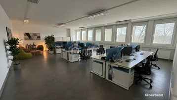 Geräumiges Großraumbüro mit mehreren Arbeitsplätzen, einem Loungebereich und großen Fenstern für viel Tageslicht.