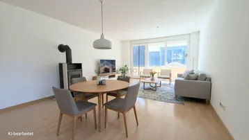 Gemütlicher Wohn- und Essbereich mit Holzboden, Kaminofen und Zugang zum Balkon.
