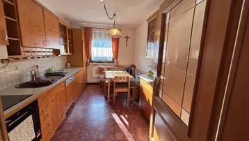 Traditionelle Holzküche mit Essbereich, Fliesenboden und Fenster für natürliches Licht.