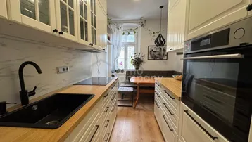 Moderne Küche mit weißen Schränken, Holzarbeitsplatten und gemütlichem Essbereich am Fenster.
