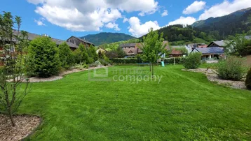 Großer grüner Rasenbereich mit Spielgeräten und Blick auf die umliegenden Berge.