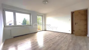 Heller Wohnraum mit Laminatboden, großen Fenstern und Zugang zu einem Außenbereich.