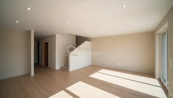 Heller, leerer Raum mit Holzfußboden und Treppenaufgang, ideal für einen offenen Wohnbereich.
