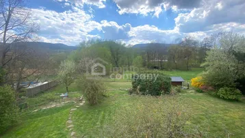 Weitläufiger Garten mit Rasenfläche, kleinem Pool und Gartenhaus, umgeben von Bäumen.