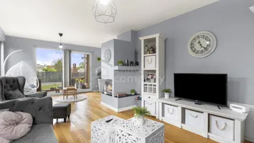 Helles Wohnzimmer mit modernem Kamin, Holzboden und großen Fenstern zum Garten.