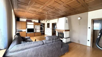 Geräumiges Wohnzimmer mit Kamin, Holzdecke und bequemer Sofagarnitur für entspannte Abende.