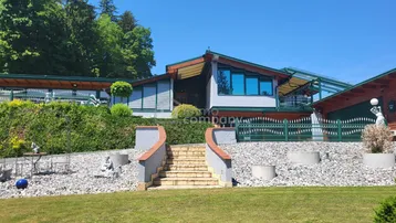 Die moderne Fassade eines Hauses mit großen Fenstern und einer Steintreppe, umgeben von einem Steingarten.