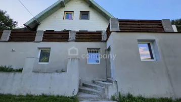Vorderansicht des Hauses mit Treppe zum Eingang und Giebeldach.