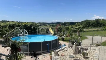 Weitläufiger Gartenbereich mit Aufstellpool, Rutsche und Panoramablick auf die umliegende Landschaft.