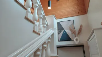 Heller Eingangsbereich mit eleganter weißer Holztreppe, moderner Dekoration und Holzbalkendecke.