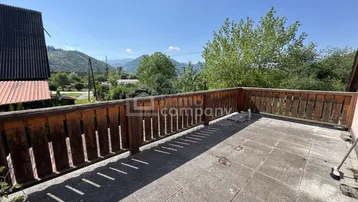 Große gepflasterte Terrasse mit Holzzaun und weitem Blick auf die umliegende Berglandschaft.
