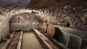Historischer Kellerraum mit Steingewölbe und Holzfässern, ideal zur Lagerung von Wein.