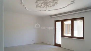 Heller Raum mit dekorativer Stuckdecke und Zugang zu einem Balkon oder einer Terrasse.