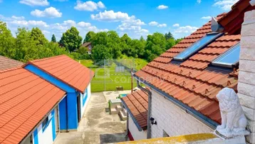Blick vom Balkon auf das Grundstück mit weiteren Gebäuden und viel Grün.