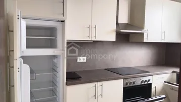 Helle Einbauküche mit weißen Schränken, Induktionskochfeld und integriertem Backofen.